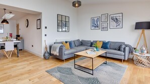 Een moderne woonkamer met een grijze bank, salontafel en kunst aan de muur.