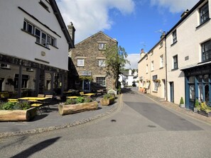 A street with buildings, outdoor seating, and a sign for 'The Little Ice Cream Shop.' - 2 Bed in Ambleside (oc-72378) (Hawkshead)