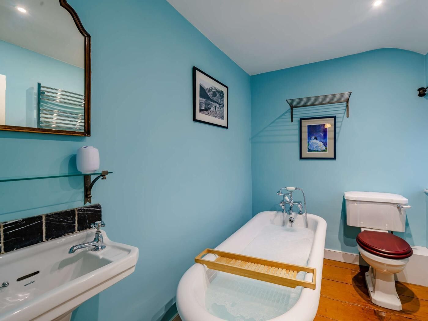 A bathroom with a sink, bathtub, toilet, and two framed pictures on the wall.