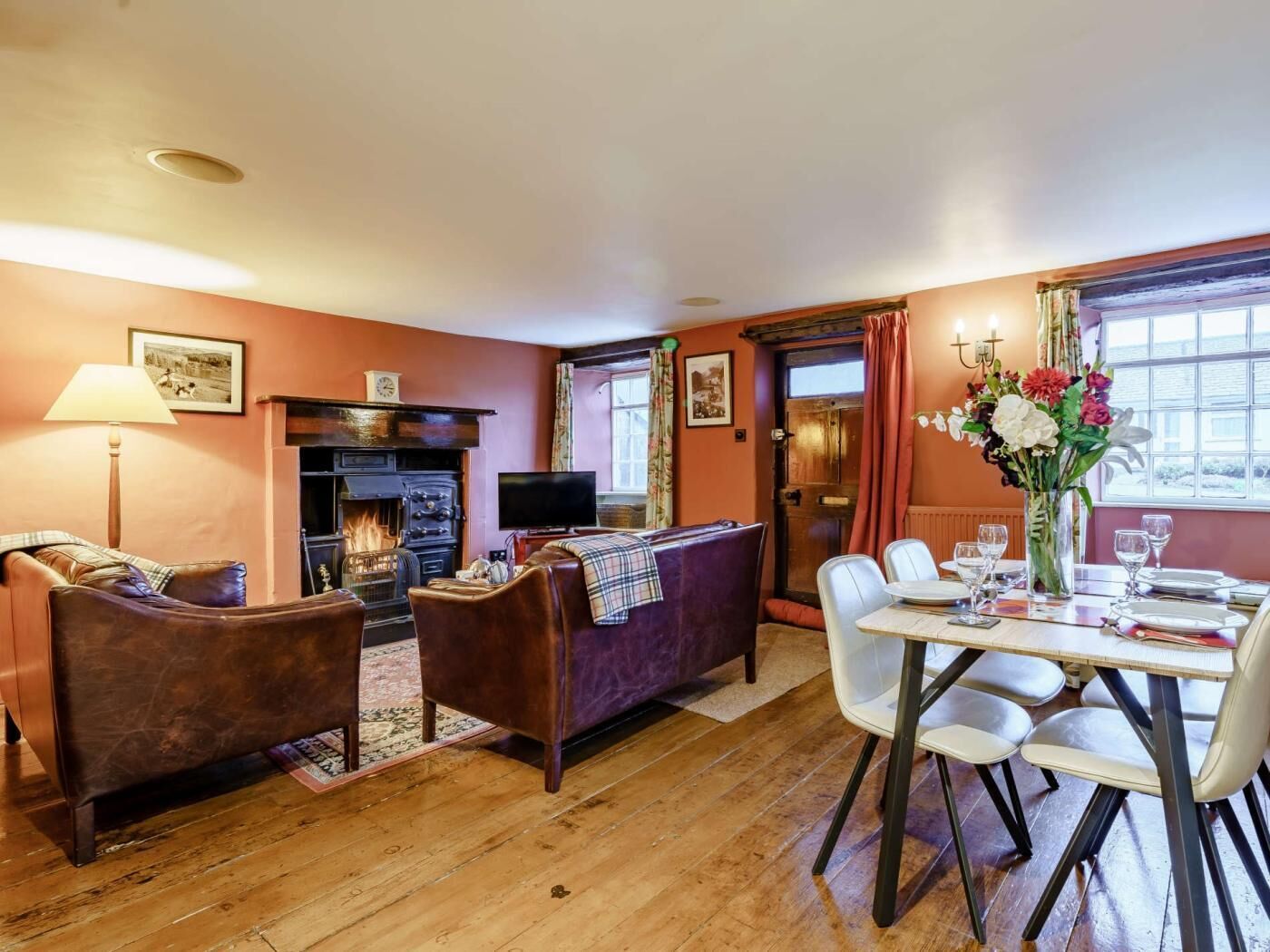 A cozy living room with a fireplace, a dining area with a table set for four, and a television.