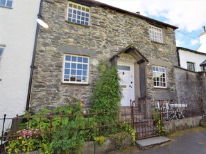 A stone building with a white door, a small window, and a metal gate. - 2 Bed in Ambleside (oc-72378) (Hawkshead)