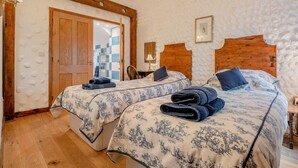 Ein Zimmer mit zwei Betten, Holz-Kopfteilen, einer Holztür, einem kleinen Tisch und einem Stuhl.