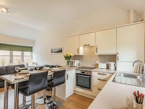 A modern kitchen with a dining area, a built-in oven, and a sink. - 2 Bed in Louth (oc-72401) (Fotherby)