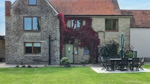 A stone house with a red-tiled roof, a green door, and a garden with a table and chairs. - 4 Bed in Gillingham (oc-80670) (West Stour)