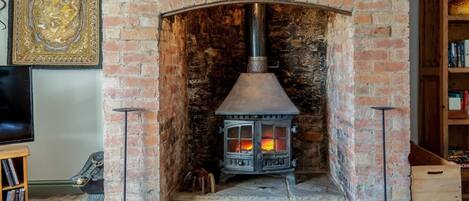 A brick fireplace with a wood-burning stove, a decorative wall piece, and a bookshelf.