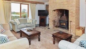 A cozy living room with a fireplace, a sofa, a television, and a view of the outdoors. - 4 Bed in Gillingham (oc-80670) (West Stour)