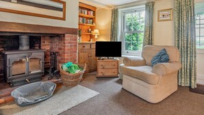 A cozy living room with a fireplace, a television, a comfortable chair, and a bookshelf. - 2 Bed in Holt (oc-ncc15) (Salthouse)