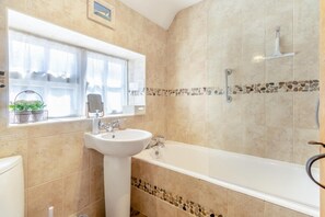 A bathroom with a bathtub, a sink, and a window with plants. - 2 Bed in Holt (oc-ncc14) (Holt)