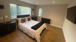 Een slaapkamer met een bed, nachtkastjes, een radiator en een raam met zonwering.
