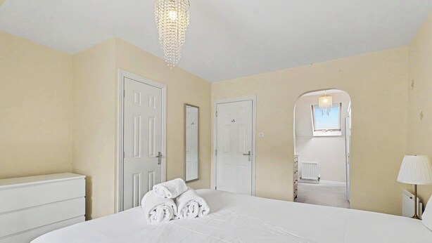 Een hotelkamer met een groot bed, witte muren en een kroonluchter.