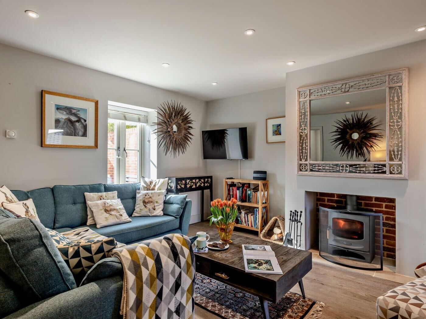 A living room with a sofa, coffee table, fireplace, bookshelf, and decorative wall art.