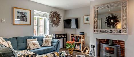 A living room with a sofa, coffee table, fireplace, bookshelf, and decorative wall art.