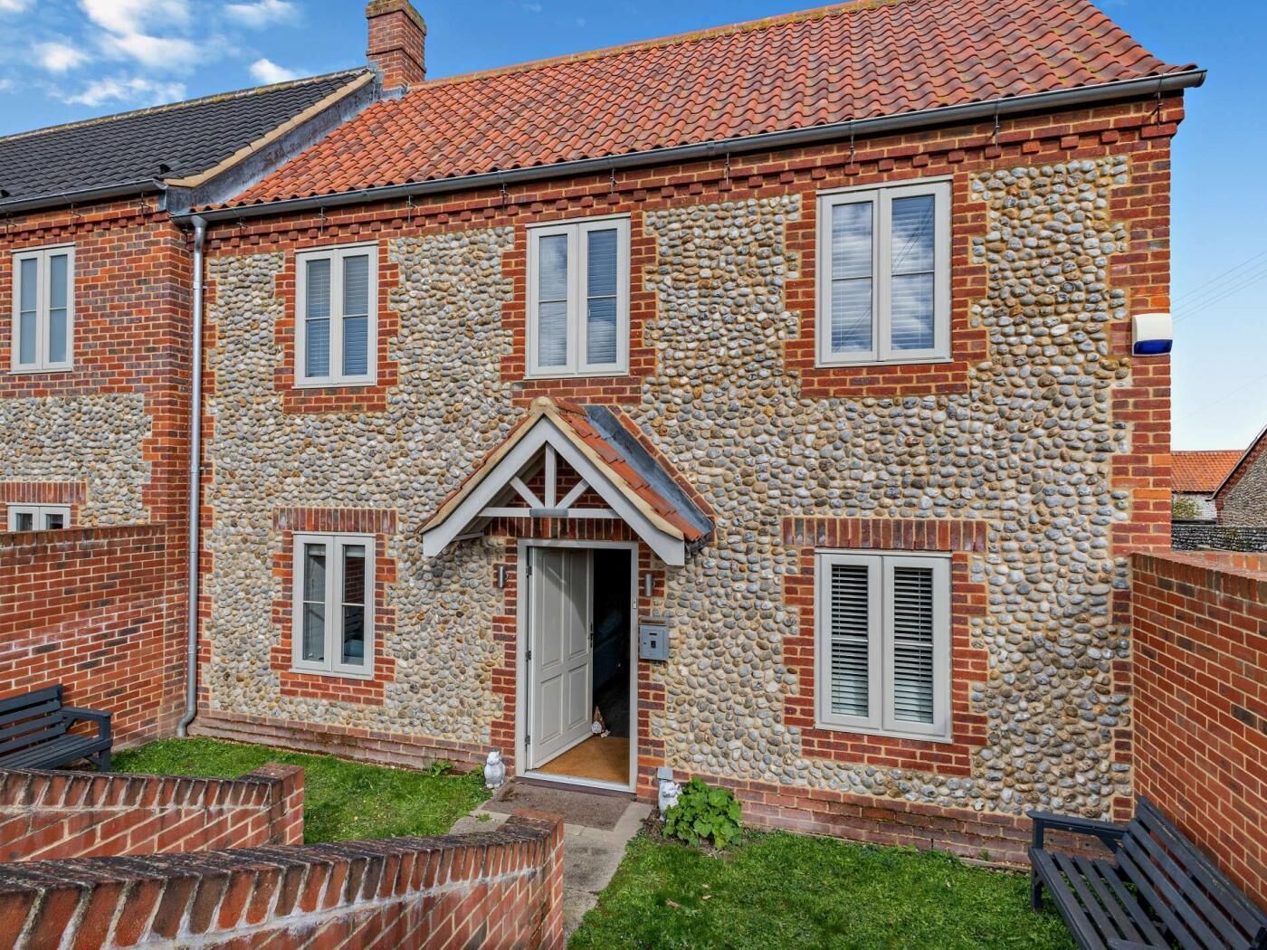 Uma casa de dois andares com fachada de pedra, várias janelas e uma porta visível.