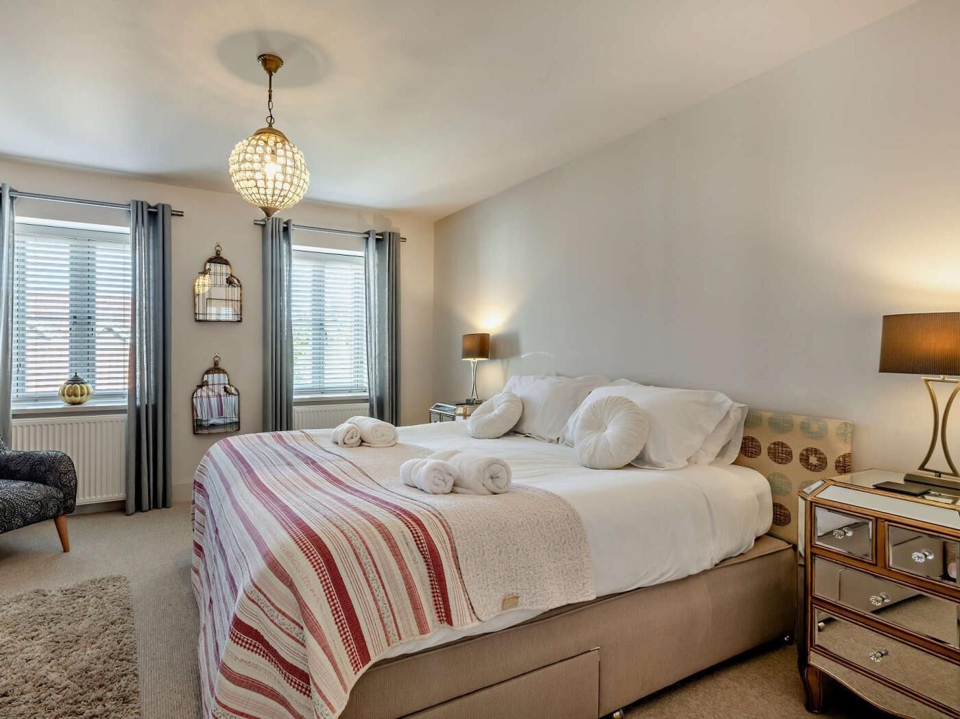 Une chambre à coucher bien aménagée, avec un grand lit, des lampes de chevet et un lustre.