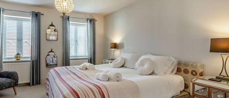Une chambre à coucher bien aménagée, avec un grand lit, des lampes de chevet et un lustre.