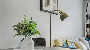 A modern living room with a round table, a white vase with green plants, a floor lamp, and a sofa with patterned cushions. - Charming 1-Bedroom Hideaway in Central Falkirk (Falkirk)