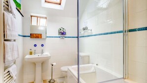 Casa de banho com cabine de chuveiro em vidro, lavatório suspenso, sanita e banheira.
