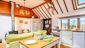 Uma cozinha acolhedora com vigas de madeira, uma mesa de jantar com cadeiras, um fogão e uma janela com vista.