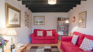 A cozy living room with two red sofas, a wooden bookshelf, and a coffee table with a lamp. - 2 Bed in Holt (oc-ncc25) (Kelling)