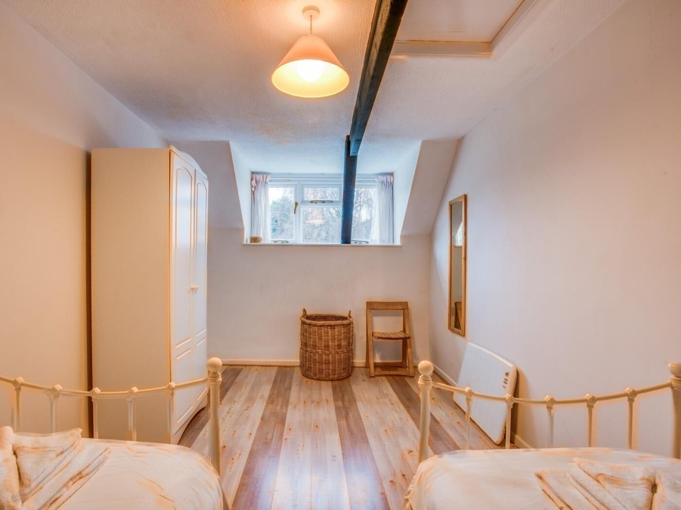 A bedroom with a wooden bed, a window, a mirror, and a ceiling light.