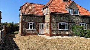 Ein zweigeschossiges Haus mit rotem Ziegeldach, Steinwänden und einem Schotterweg.