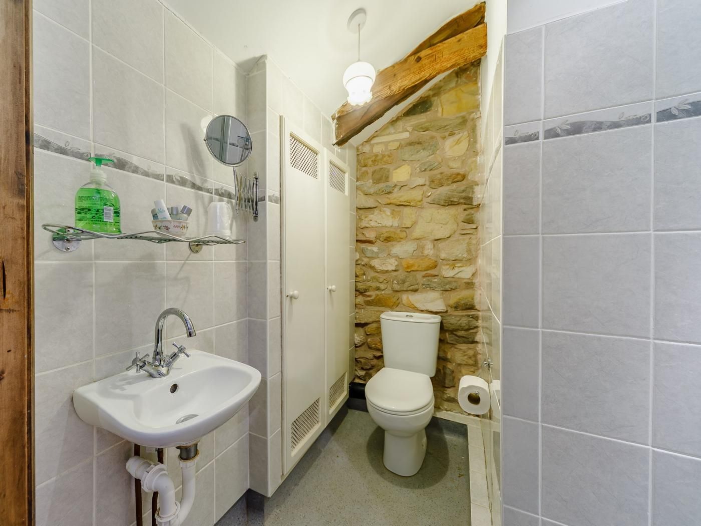 A bathroom with a white sink, a mirror, a toilet, and a shower area.