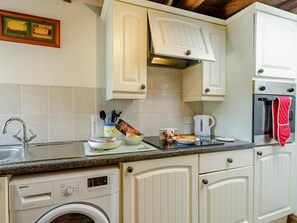 A kitchen with a washing machine, a coffee maker, and a red oven mitt. - 2 Bed in Brampton (oc-73578) (Low Row)