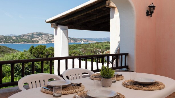 A table set for dining with a view of the sea and hills. - Casa Tozzi by Wonderful Italy (Arzachena)