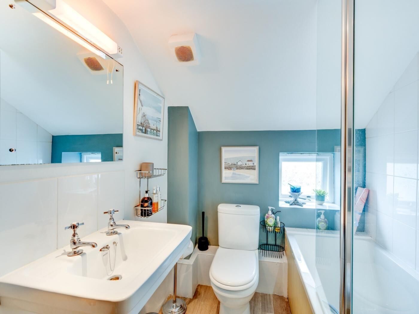 Et moderne badeværelse med en hvid vask, toilet og en brusekabine i glas.