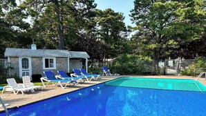 A swimming pool with lounge chairs and a small building in the background.