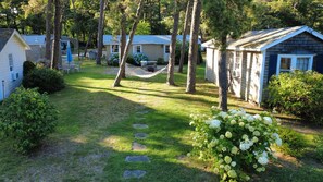 Un terrain de camping doté de plusieurs cabanes, d’un hamac et d’un jardin où poussent des hortensias.