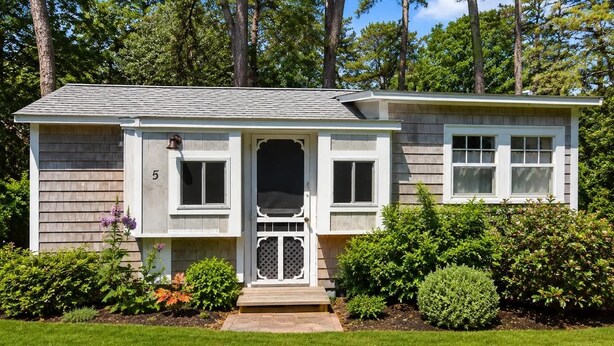 A single-story house with a front porch, a number '5' on the door, and a well-maintained lawn.