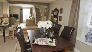 A dining area with a table set for four, a vase of white flowers, and a bottle of wine. - 1 Bed in Pateley Bridge (oc-g0015) (Wilsill)