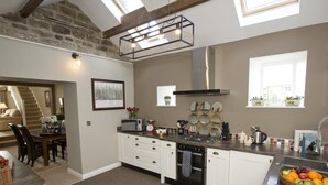 A modern kitchen with a central island, a dining area with a staircase, and a view of the outside. - 1 Bed in Pateley Bridge (oc-g0015) (Wilsill)