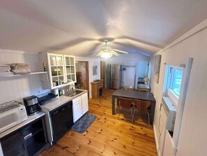 A compact kitchen with a dishwasher, microwave, and a ceiling fan.