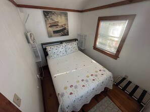 A bedroom with a bed, a window, a painting, and a radiator. - Beautiful Two Bedroom Cabin on Campground (Yarmouth)