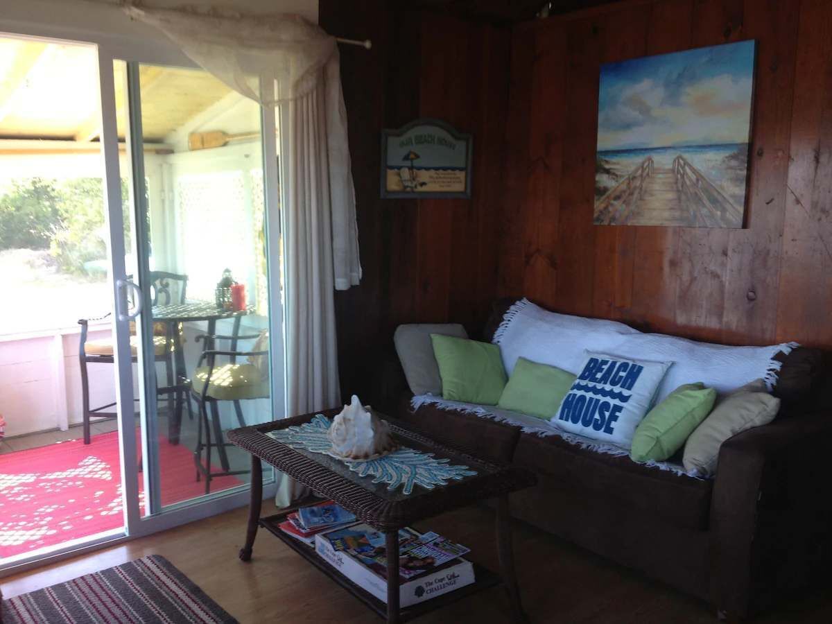 A cozy room with a wooden sofa, a glass table, and a painting on the wall.
