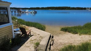 A lakeside property with a dock, a chair, and a table. - Charming 1 Bedroom Cottage on the Water! (South Dennis)