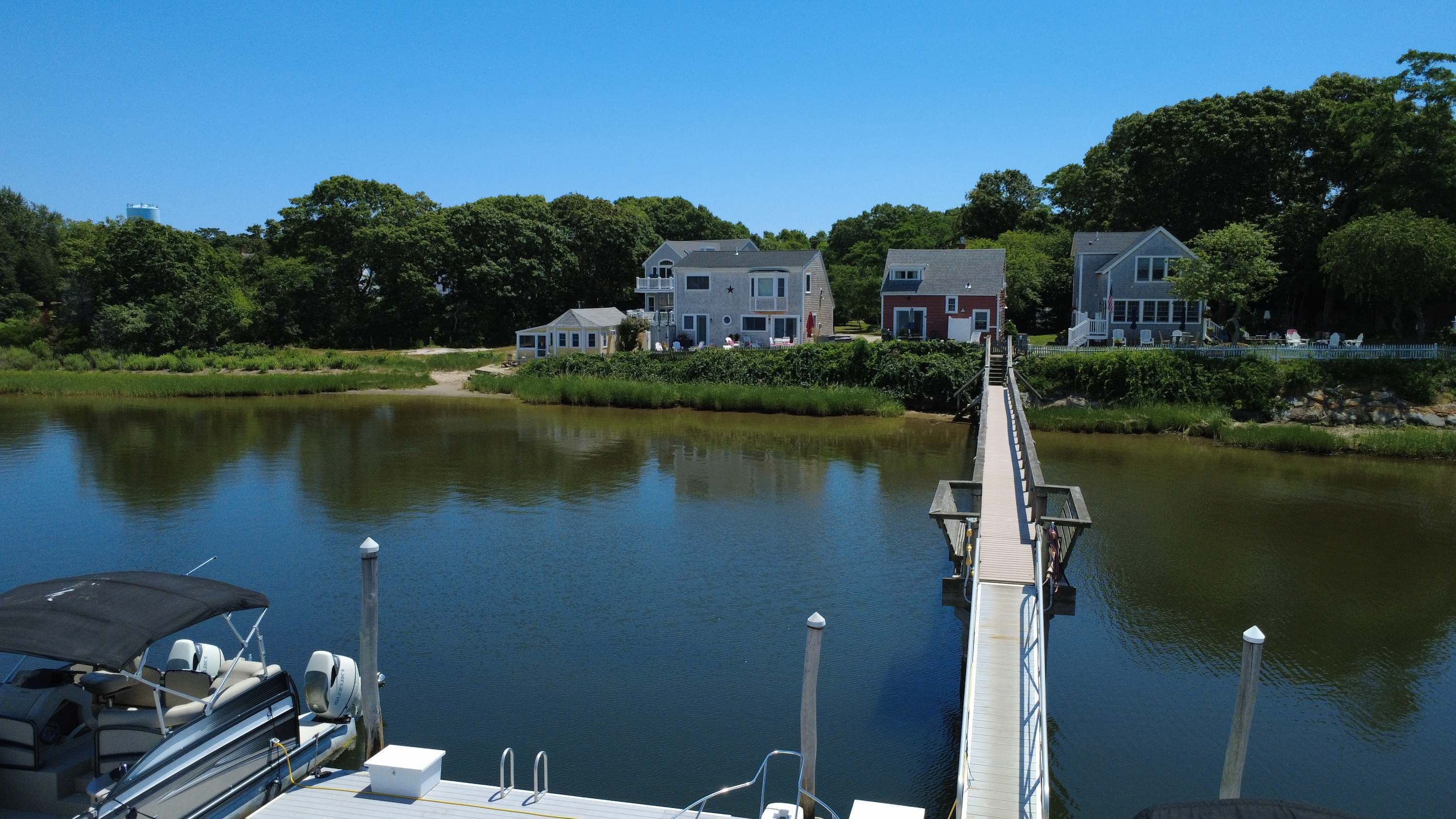 A calm lake with a dock leading to a house with a large window and a star on the roof.