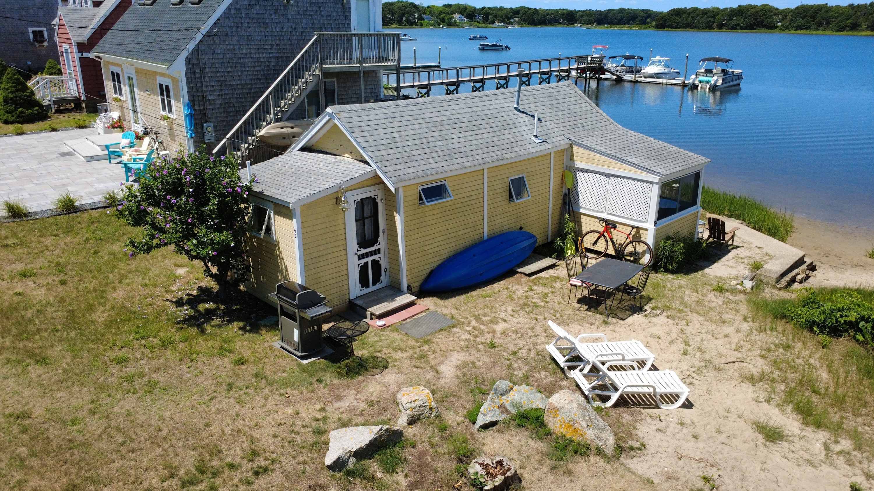 A waterfront property with a covered patio, outdoor seating, and a dock.