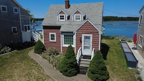A two-story house with a front porch, a small deck, and a view of a lake. - 2 Bedroom House on the Water! (South Dennis)