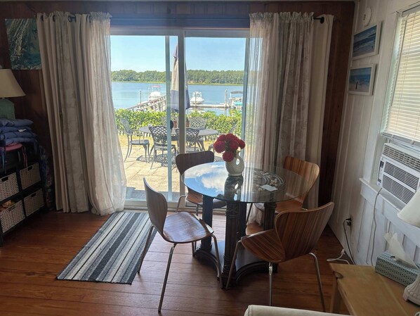 A room with a glass table, chairs, a view of the sea, and a wooden floor. - 2 Bedroom House on the Water! (South Dennis)
