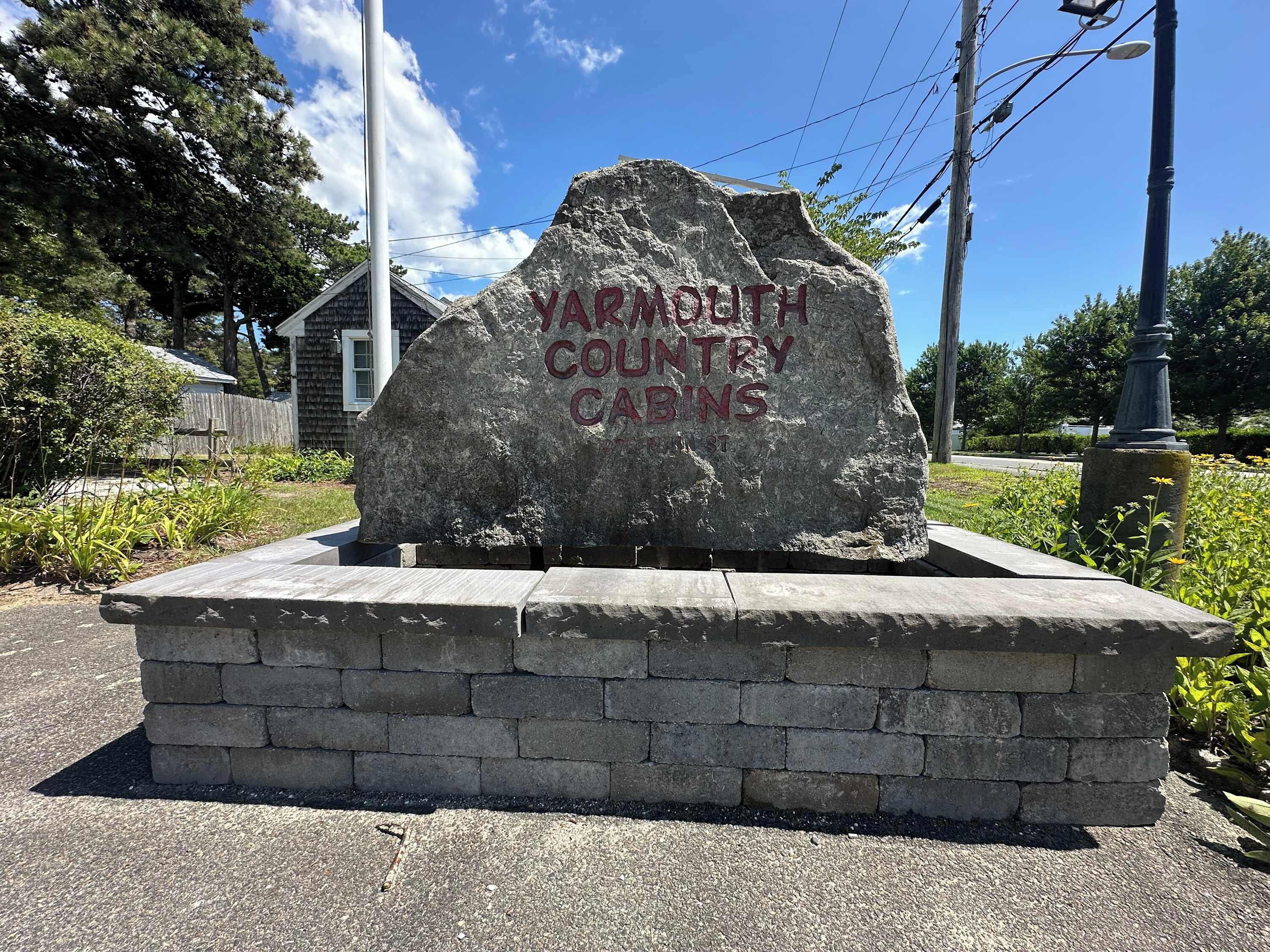 Un monument en pierre portant l’inscription « YARMOUTH COUNTRY CABINS » sur une zone pavée, avec une base en briques.