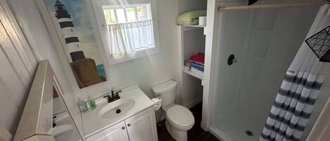 A compact bathroom with a toilet, sink, and shower area.