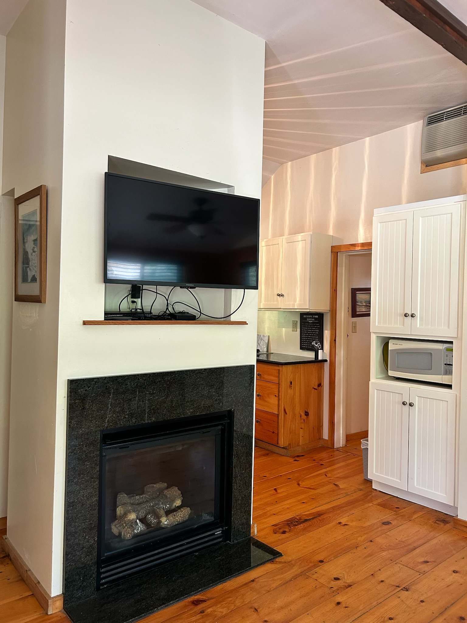 Una sala de estar moderna con chimenea, televisor montado y armarios de madera.