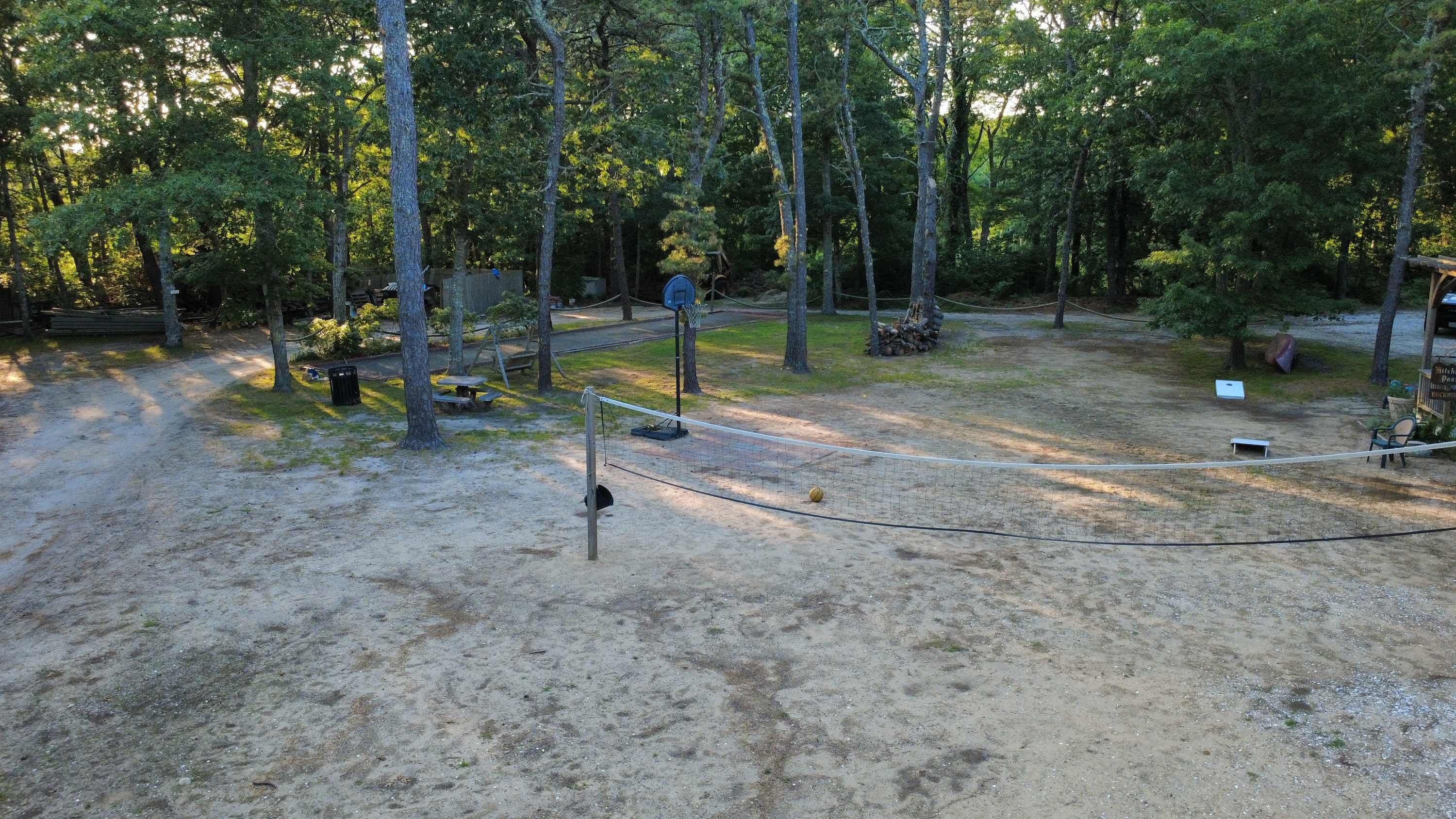 A campground with a volleyball net, picnic tables, and a sign for a post office.