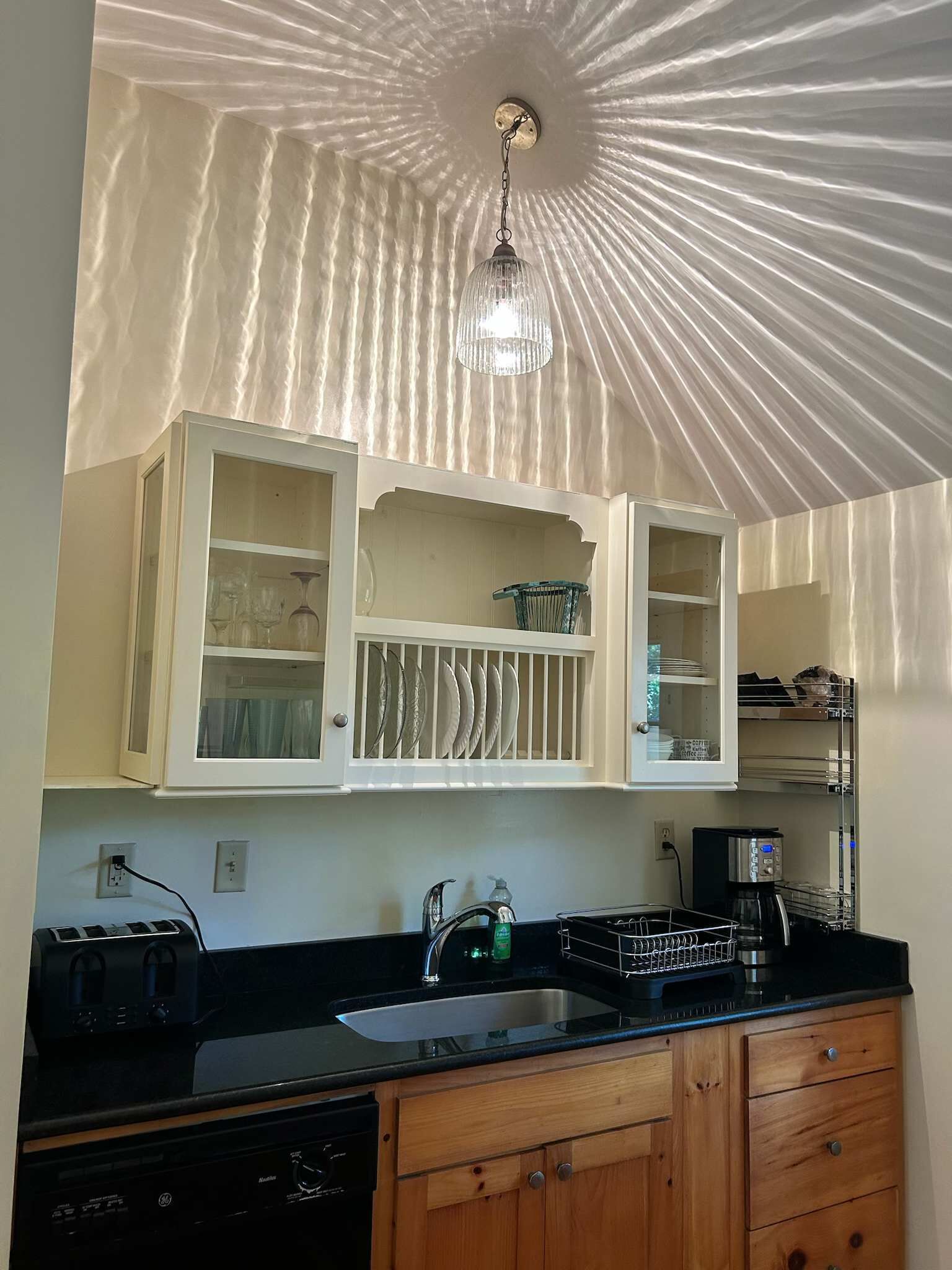 Una cocina equipada con lavavajillas, cafetera y pileta.