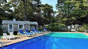 Une piscine avec des chaises longues et un petit bâtiment en arrière-plan.