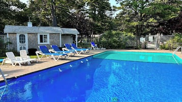 A swimming pool with lounge chairs and a small building in the background.