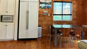Une cuisine équipée d’un réfrigérateur, d’un four à micro-ondes et d’un coin repas avec des chaises et une table.
